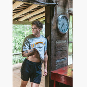 Man inside of cabin wearing black lounge shorts and grey t-shirt.