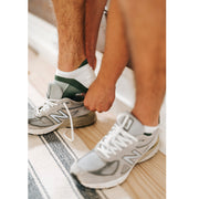 Close up of man putting on shoe wearing black/white performance ankle sock.