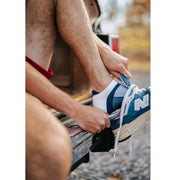 Close up of man putting on shoe over blue/white performance ankle sock.