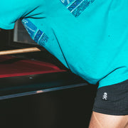 Man wearing black mesh shots with white skull leaning against pool table.