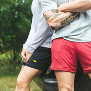 Two men standing in front a truck wearing lounge shorts. One burgundy one black.