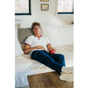 Man laying on couch wearing white tshirt and navy blue lounge pants. 
