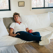 Man laying on couch wearing white tshirt and navy blue lounge pants. 