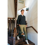 Man walking down stairs wearing a black sweater and olive lounge pants.