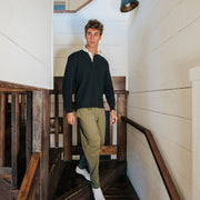 Man walking down stairs wearing a black sweater and olive lounge pants.