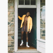 Man wearing yellow/red/blue stripe slim fit boxers and an open yellow dress shirt.