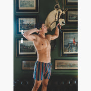 Shirtless man wearing yellow/red/blue stripe slim fit boxers and an open yellow dress shirt.