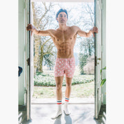Front shot of shirtless man walking into doorway wearing pink slim fit boxers with white dots 