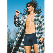 Shirtless man wearing open robe and blue boxer briefs holding a golf club on his shoulder.