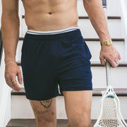 Man walking down stairs shirtless wearing navy blue lounge short.