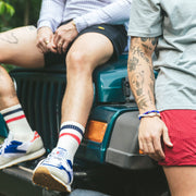 Two men on Jeep wearing tech varsity socks and lounge shorts.