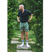 Man standing in garden wearing pink palms print lounge shorts.