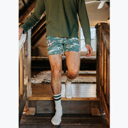 Close up of man walking down stairs wearing long sleeve green t-shirt and green slim fit boxers with clouds, horses and trees printed on.