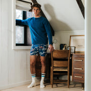 Man standing in bedroom wearing navy blue crewneck and navy slim fit boxers with horses, trees, and clouds.