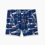 Pair of navy blue slim fit boxers with cowboys, trees and clouds printed on laid flat against grey background.